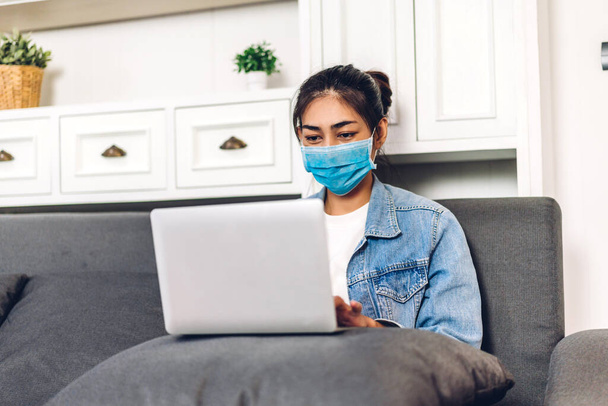 Młoda azjatycka kobieta za pomocą komputera laptopa pracy i wideokonferencji spotkanie online czat w kwarantannie dla koronawirusa noszenie maski ochronnej w home.work od koncepcji domu - Zdjęcie, obraz