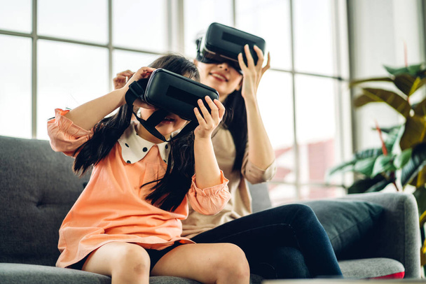 Portrait of enjoy happy love asian family mother and little asian girl child smiling and having fun using glasses of virtual reality headset.concept of modern technology - Photo, Image