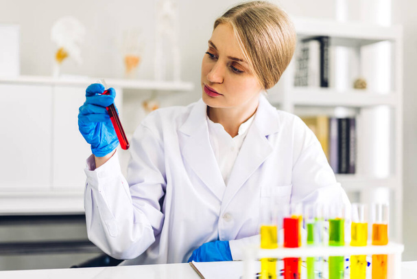 Ammattimainen tiedemies nainen tutkimus ja työskentely tekee kemiallisen kokeen samalla analysoimalla ja sekoittamalla nestettä koeputkessa. - Valokuva, kuva