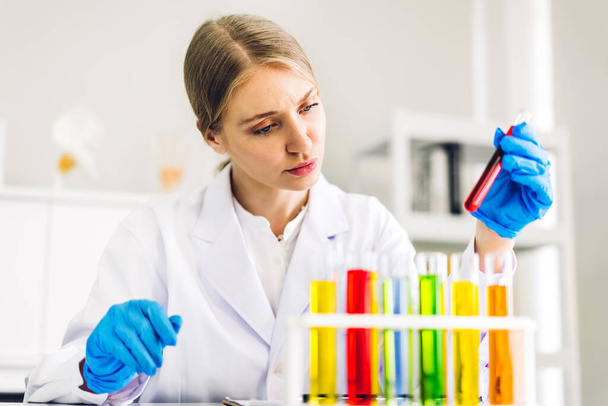 Ammattimainen tiedemies nainen tutkimus ja työskentely tekee kemiallisen kokeen samalla analysoimalla ja sekoittamalla nestettä koeputkessa. - Valokuva, kuva