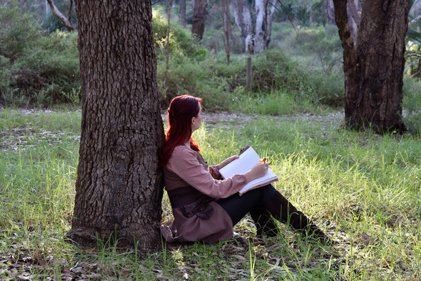  retrato de una chica pelirroja con ropa medieval de fantasía de un aventurero errante. luz natural en un bosque arbolado. - Foto, Imagen