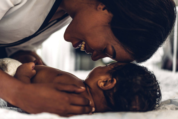 Retrato de desfrutar de amor feliz família afro-americana mãe brincando com adorável pouco afro-americano baby.Mom tocando com bonito filho momentos bom tempo em um quarto branco.Amor de família negra - Foto, Imagem