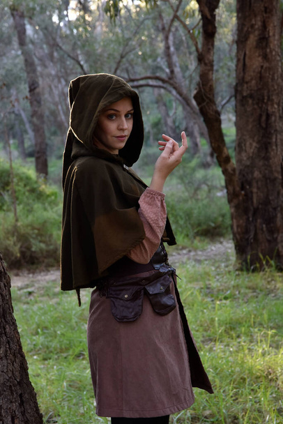  Portret rudej dziewczyny ubranej w średniowieczne ubrania wędrownego poszukiwacza przygód. naturalne światło w lasach leśnych. - Zdjęcie, obraz