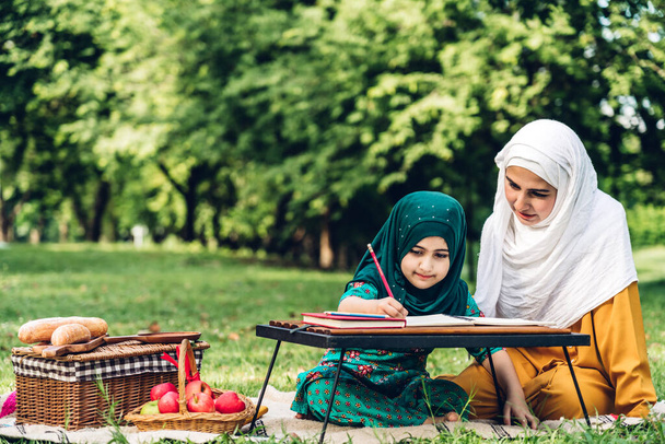 Portrait of happy religious enjoy happy love asian family arabic muslim mother and little muslim girls child with hijab dress smiling and having fun moments good time in summer park - Photo, image