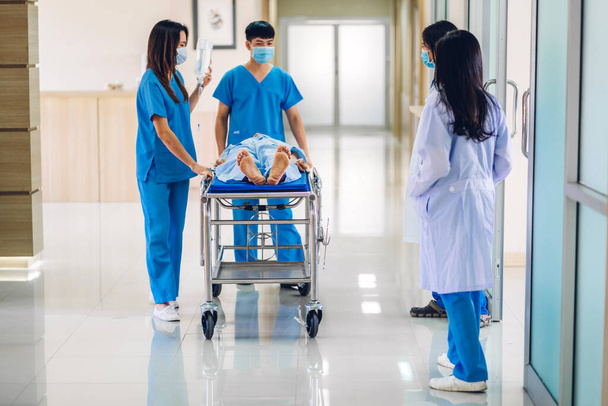 Group of professional medical doctor team and assistant with stethoscope in uniform taking seriously injured patient to operation emergency theatre room in hospital.health medical care concept - Foto, afbeelding