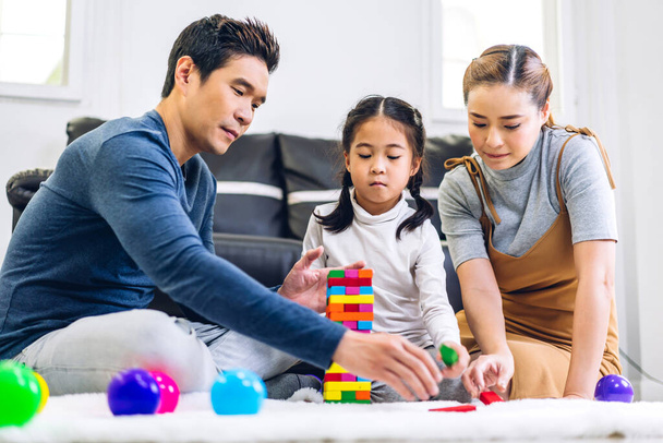Portret cieszyć się szczęśliwą miłością azjatyckiej rodziny ojciec i matka z małą azjatycką dziewczyną uśmiecha się bawiąc się zabawką zbudować drewniany blok gra planszowa w chwilach dobry czas w domu - Zdjęcie, obraz