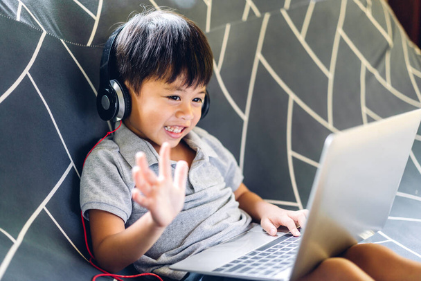 Маленький школьник учится и смотрит на ноутбук, делая домашнюю работу, изучая знания с помощью системы онлайн-образования e-learning. - Фото, изображение
