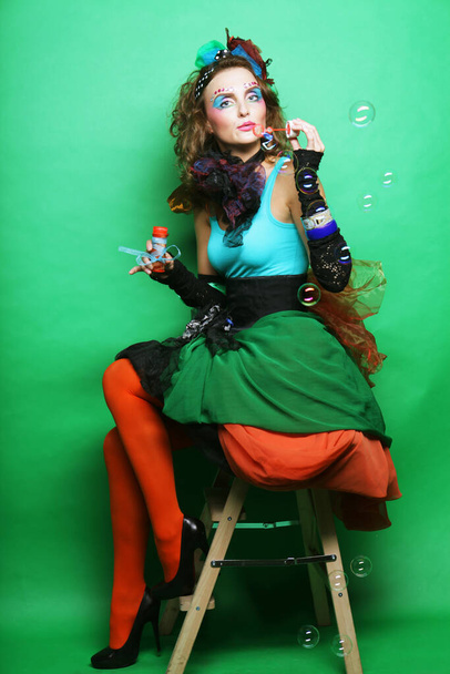 Young model in carnaval dress with creative make-up blows bubbles. Doll style. - Foto, Imagen