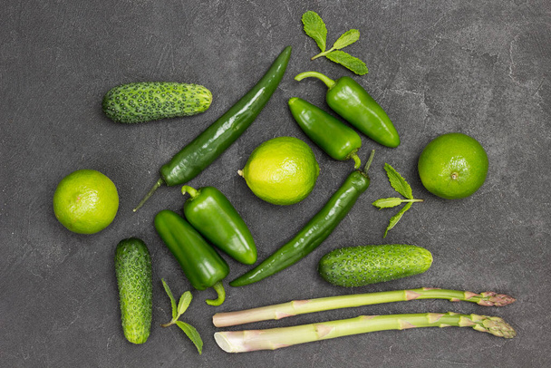 Green peppers, asparagus, cucumbers and limes on the table. Black background. Flat lay - Foto, Imagen