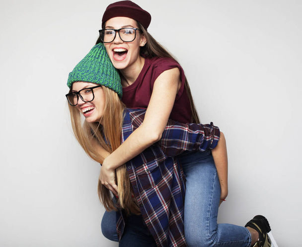 Two young beautiful smiling hipster girls in trendy summer clothes. - Foto, afbeelding