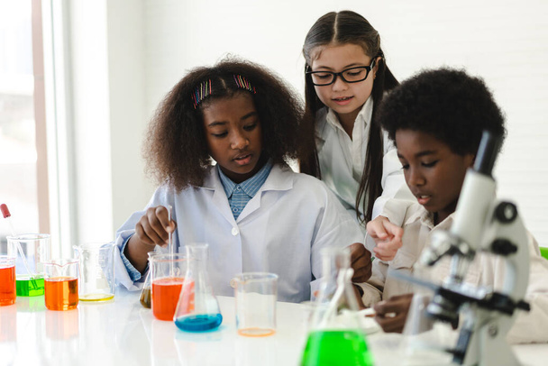 Группа милых подростков изучает исследования и проводит химический эксперимент, анализируя и смешивая жидкость в пробирке на лабораторных занятиях в школе. Образование - Фото, изображение