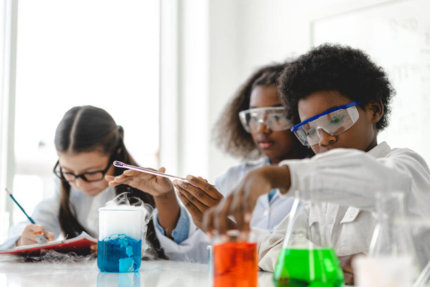 Grupo de adolescentes lindo niño estudiante aprendiendo investigación y haciendo un experimento químico mientras se hace el análisis y mezcla de líquido en tubo de ensayo en la clase de laboratorio experimento en la escuela.Educación - Foto, Imagen