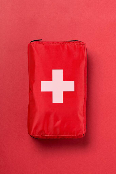 Red first aid medical kit bag over red background flat lay top view from above - 写真・画像