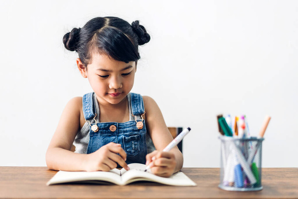 Školní dítě holčička učení a psaní v notebooku s tužkou dělat domácí úkoly. - Fotografie, Obrázek
