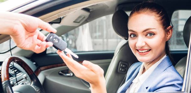 Sales dealer het geven van autosleutels voor nieuwe auto met zakenvrouw glimlachend terwijl zittend in een car.sale en huurauto concept - Foto, afbeelding