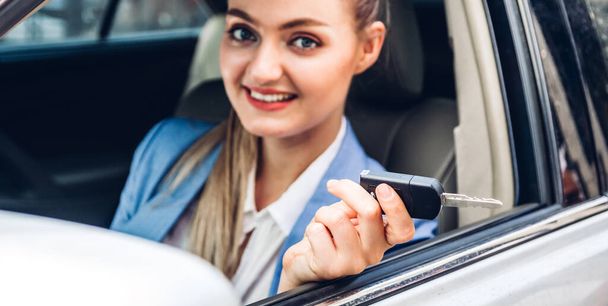 Obchodní žena při pohledu na kameru a ukazování klíčů od auta při sezení v autě - Fotografie, Obrázek