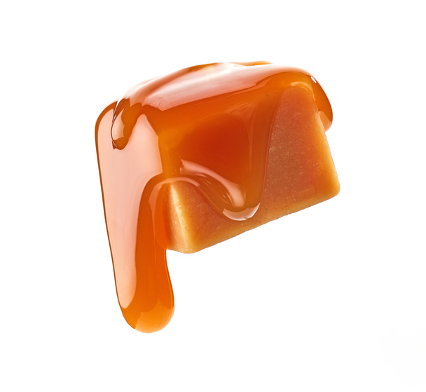 karamelsaus stromend op zwevende karamel snoep geïsoleerd op witte achtergrond - Foto, afbeelding