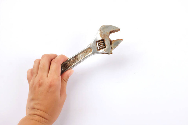 Mano sosteniendo una vieja llave oxidada sobre un fondo blanco. - Foto, imagen