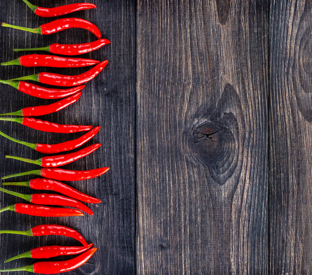 The top view of spicy red chili pepper on wooden surface. Selective focus - Zdjęcie, obraz