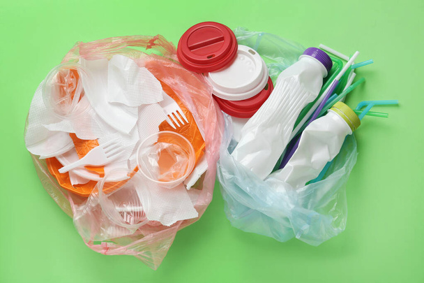 Pile of different plastic items on green background, flat lay - Fotoğraf, Görsel