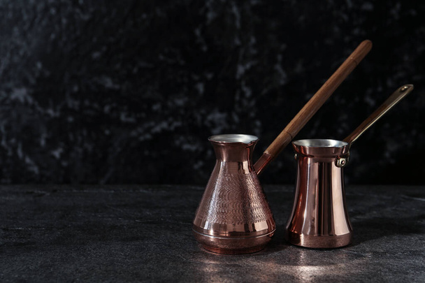 Beautiful copper turkish coffee pots on grey table. Space for text - Zdjęcie, obraz