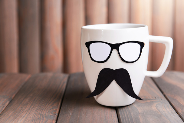 Cup with mustache on table on wooden background - Photo, Image