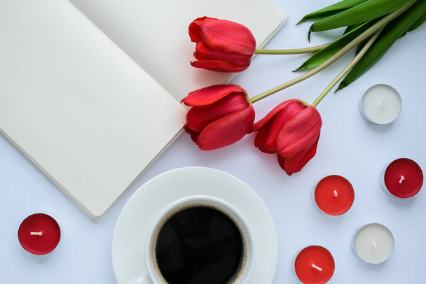 Ułóż puste miejsce na tekst. Czerwone tulipany świece Biały kubek kawy śniadanie rano. Wakacyjna przeszłość. Kartka z życzeniami. Walentynki Dzień Matki Kobiet. Widok góry. Układy płaskie - Zdjęcie, obraz