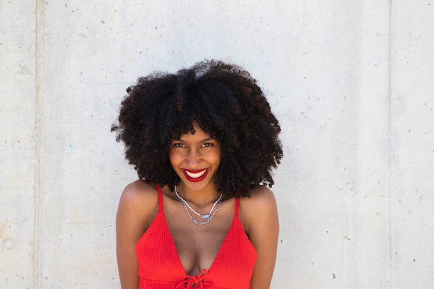 beautiful afro american woman smiling and looking at the camera doing different poses and gestures with her face. The woman is wearing a red top and red lipstick. Concept happiness - Photo, Image