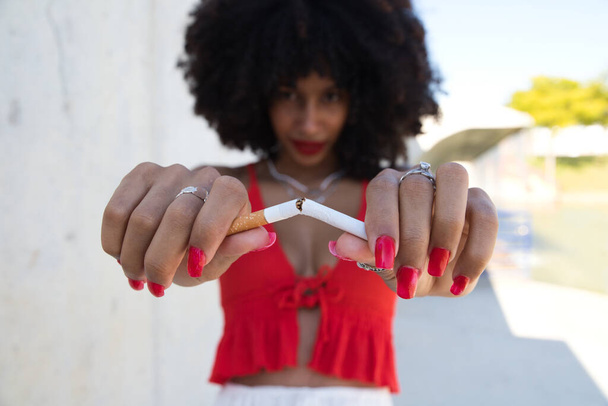 schöne Afroamerikanerin, die sich eine Zigarette bricht und in die Kamera schaut. Kampagne zur Sensibilisierung gegen das Rauchen. Gesundheitskonzept. Rauchfreie Welt - Foto, Bild