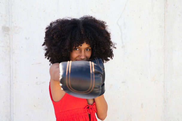 Bella donna afro-americana con i guanti da boxe che rivendica i diritti delle donne contro i maltrattamenti e il cancro al seno. Concetto di diritti delle donne. - Foto, immagini
