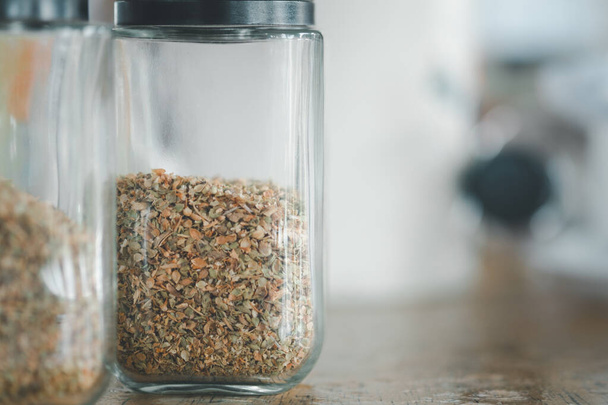 Dried oregano in a glass jar on table in a pizza place - Фото, изображение