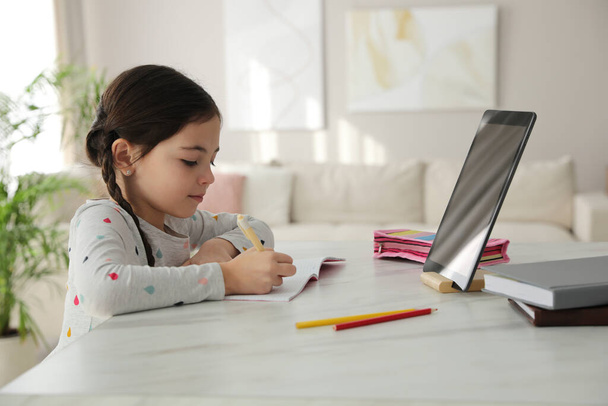 Little girl doing homework with modern tablet at home - Fotografie, Obrázek