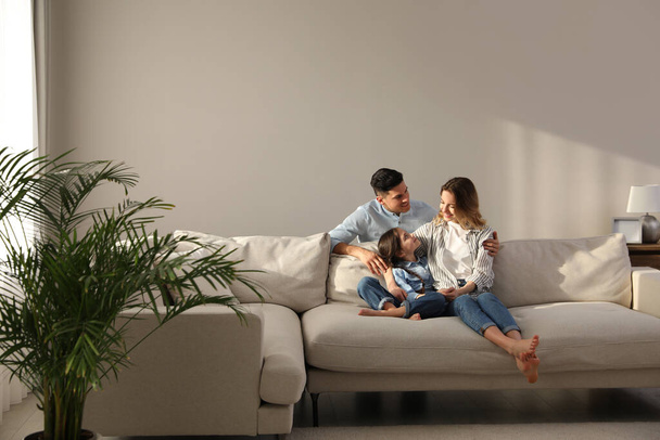 Família com pequena filha descansando no sofá na sala de estar - Foto, Imagem