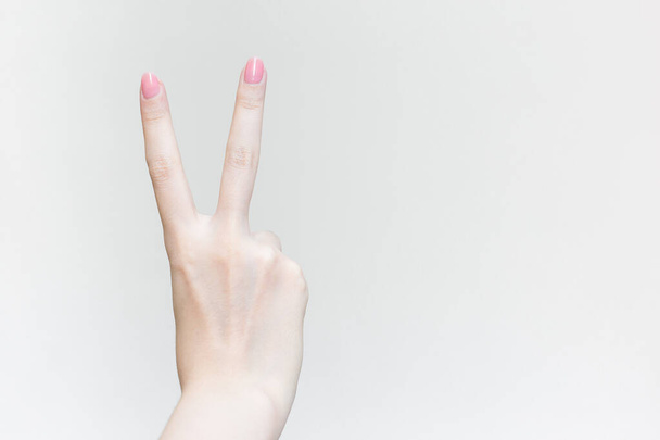 Beautiful female hand shows heart symbol as victory sign in manicure concept. - Foto, Imagem