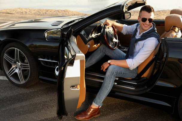 Handsome young man in luxury convertible car outdoors - Φωτογραφία, εικόνα