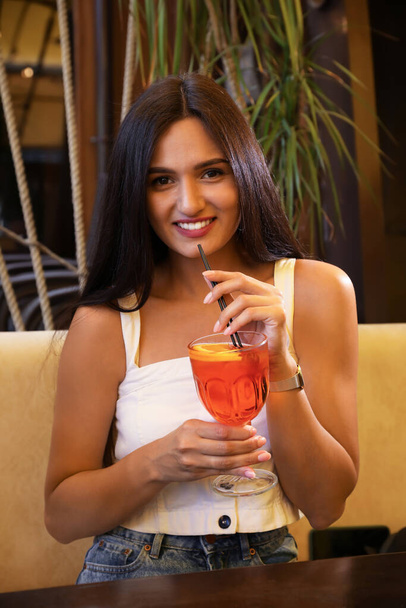 Young woman with Aperol spritz cocktail resting at restaurant - Фото, зображення