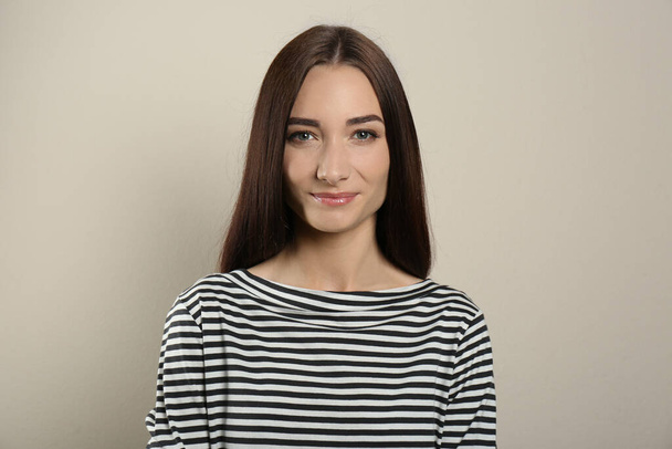 Portrait of pretty young woman with gorgeous chestnut hair on light background - Fotó, kép