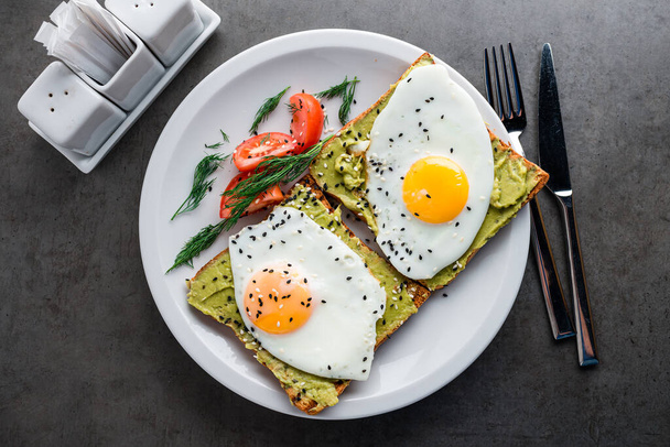 Gesundes Frühstück. Avocado-Toast mit gebratenem Ei, Ei und Avocado-Sandwich, Vollkorn-Toast mit pürierter Avocado, Spiegeleier - Foto, Bild