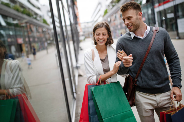 Beautiful young couple enjoying in shopping, having fun together. Consumerism, love, dating, lifestyle concept - Photo, image