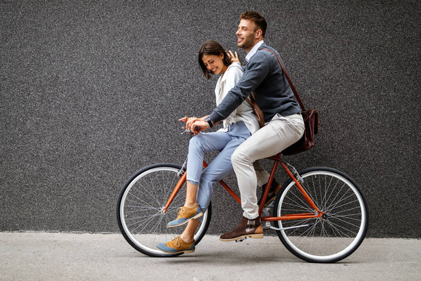 Portrait of happy young couple in love riding a bicycle and having fun together outdoor - Фото, изображение
