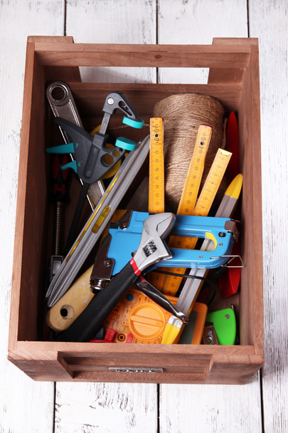 Wooden box with different tools, on wooden background - Фото, изображение
