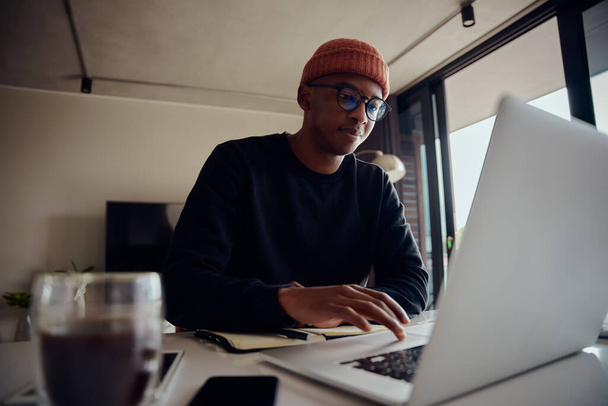 African American male working from home and browsing on his laptop. African American male using electronics to work from home. High quality photo - Φωτογραφία, εικόνα