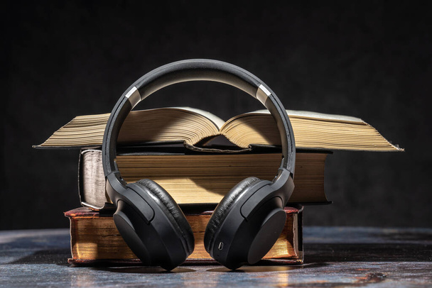 Kopfhörer liegen neben alten Büchern. Hörbuchkonzept - Foto, Bild
