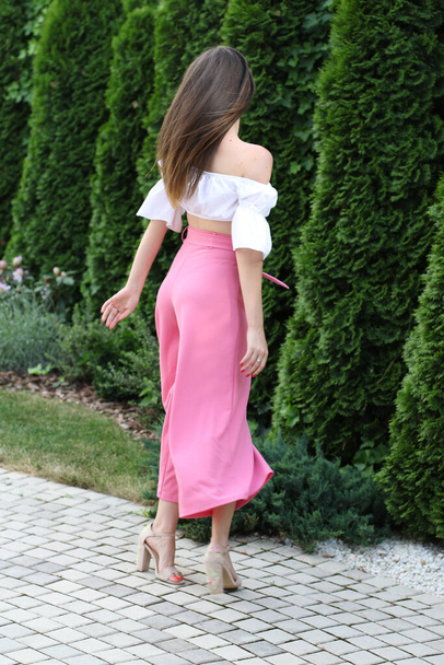 Fotoshoot van een model gekleed met roze broek terwijl ze draait - Foto, afbeelding