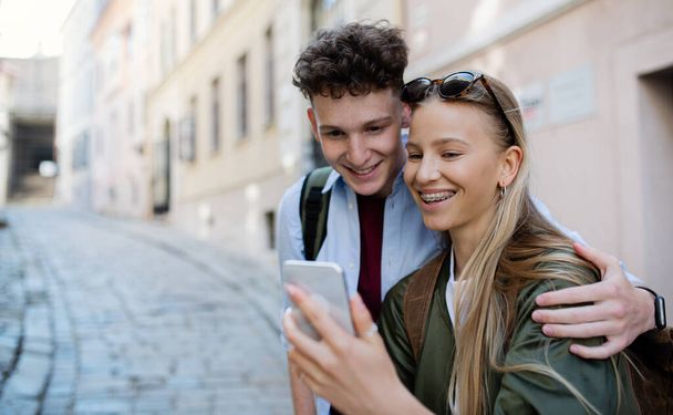 Jóvenes viajeros en pareja con teléfono inteligente en la ciudad de vacaciones, turismo. - Foto, imagen