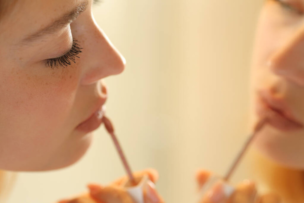 Close up of a serious woman painting lips applying lipstick - Zdjęcie, obraz