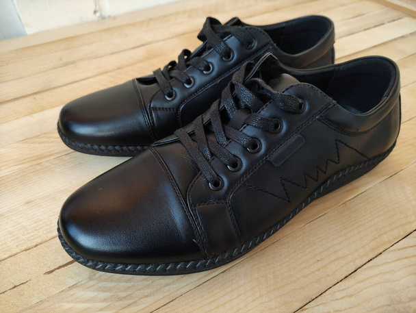 Μαύρα δερμάτινα αθλητικά παπούτσια σε ξύλινο φόντο - Φωτογραφία, εικόνα
