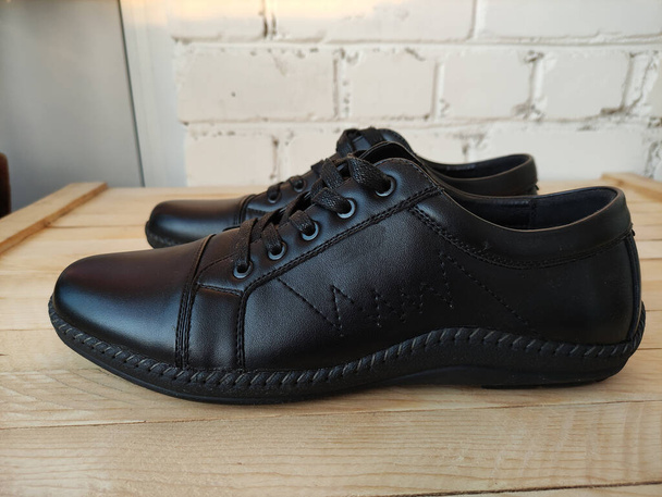 Fekete bőr sport cipő egy fa háttér - Fotó, kép