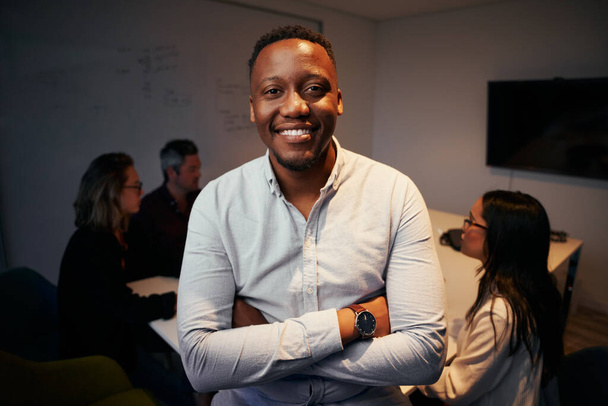 Portrait of smiling african business manager posing in front of his colleague working at background - Photo, Image