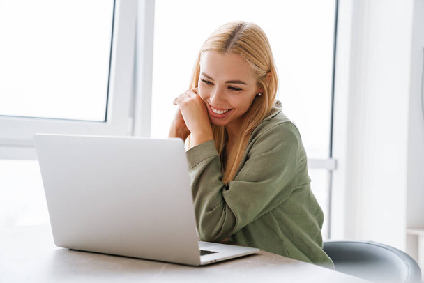 Onnellinen hymyilevä nuori nainen kannettavan tietokoneen kanssa, jolla on video puhelu kotona toimistossa - Valokuva, kuva